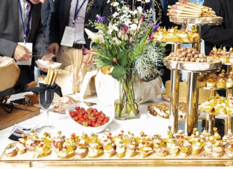 people dressed in suits at food table with appetizers